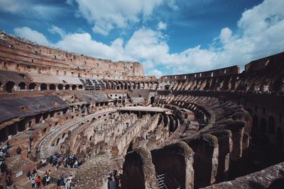 People at historic coliseum against sky