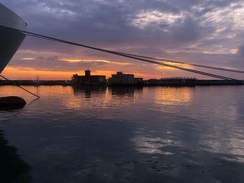 Silhouette bridge over sea against sky during sunset