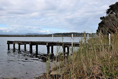 Pier on sea against cloudy sky