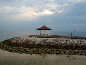 Pagoda style hut on sea shore against sky