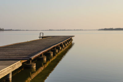 Pier over lake against clear sky