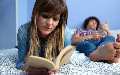 Young woman reading book on bed