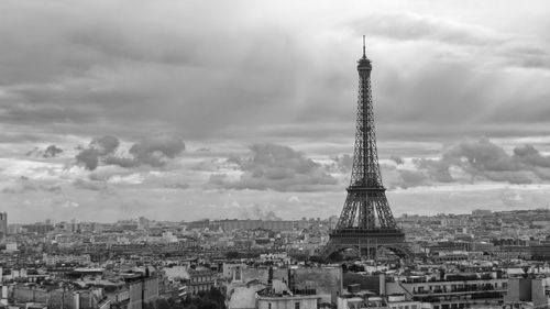 Tower in city against cloudy sky