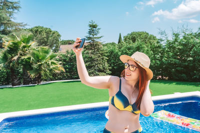 Woman taking selfie by pool