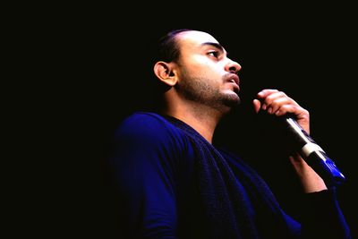 Low angle view of singer singing against black background