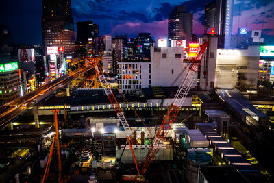 High angle view of cranes at construction site in city at night