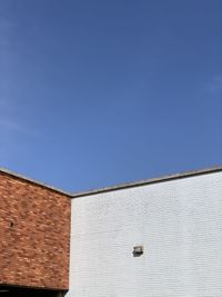Low angle view of building corners against blue sky