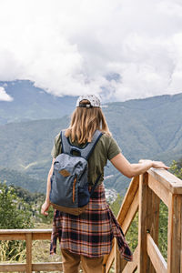 Rear view of woman standing on mountain against sky