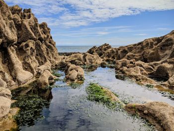 Rock formation on beach against sky