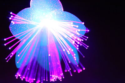 Low angle view of illuminated lighting equipment against black background