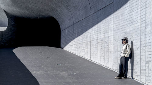 A woman standing on footpath against wall