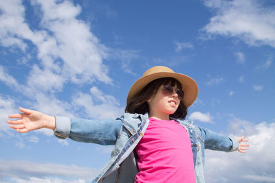 Little girl playing in freedom with arms raised with the sky in the background