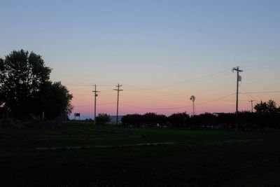 Electricity pylon on field against sky at sunset