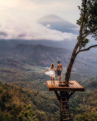 People sitting on mountain against sky