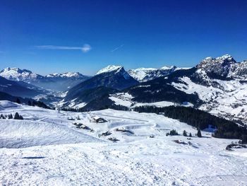 Scenic view of snowcapped mountains against blue sky