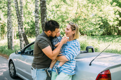 Mom, dad and little son in a convertible car. summer family road trip to nature