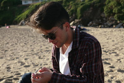 Young man wearing sunglasses at sandy beach