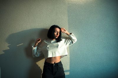 Portrait of young woman standing against wall