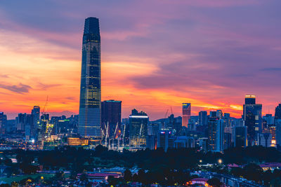 Illuminated buildings in city against sky during sunset