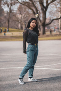 Portrait of young woman standing on road in city