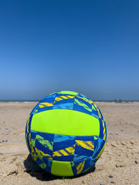 A sandy beach holding a football ball.