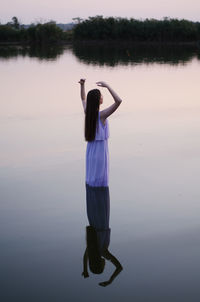 Woman with arms raised standing in lake