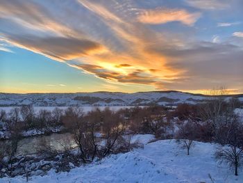 Scenic view of snow covered field against sky at sunset