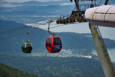 Overhead cable cars over mountains against sky