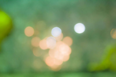 Defocused image of illuminated lights against sky at night