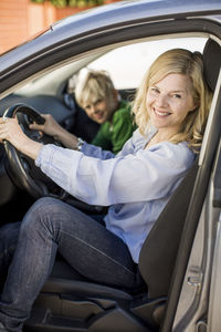 Portrait of happy woman driving car while sitting by son