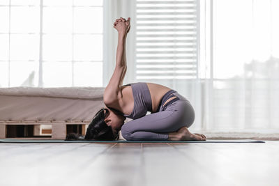 Woman doing yoga at home during day