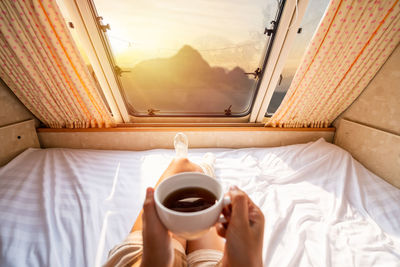 Man holding coffee cup on bed