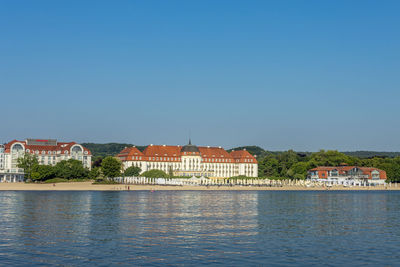 Buildings by city against clear blue sky