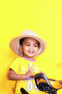 Smiling boy with wearing hat against yellow wall