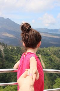Cropped image of parent holding daughter hand against landscape