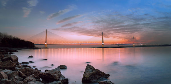 Bridge over bay against sky during sunset