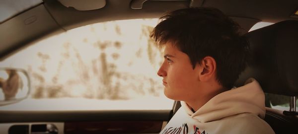 Side view of young man sitting in car