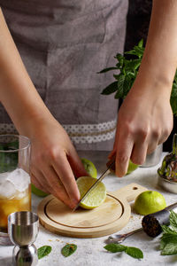 Hands cut fresh lime for mojito cocktail close up