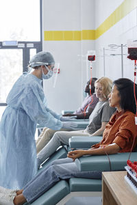 Nurse instructing woman donating blood in hospital