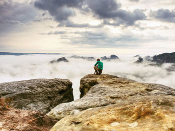 Photographer looks into fall and  prepare camera to takes impressive photos of misty fall mountains.