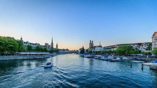 Boats sailing in river with city in background