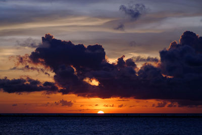 Scenic view of sea against dramatic sky during sunset