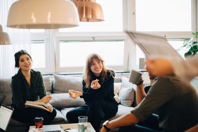 Happy coworkers discussing during coffee break at creative office