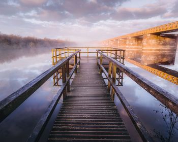 Footbridge against sky during sunset