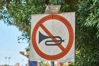 Close-up of no honk sign against trees