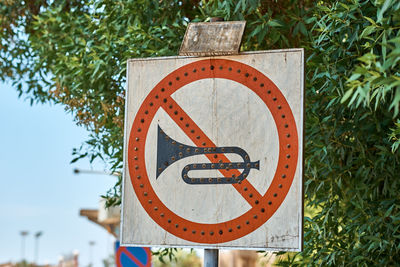 Close-up of sign on plant against trees