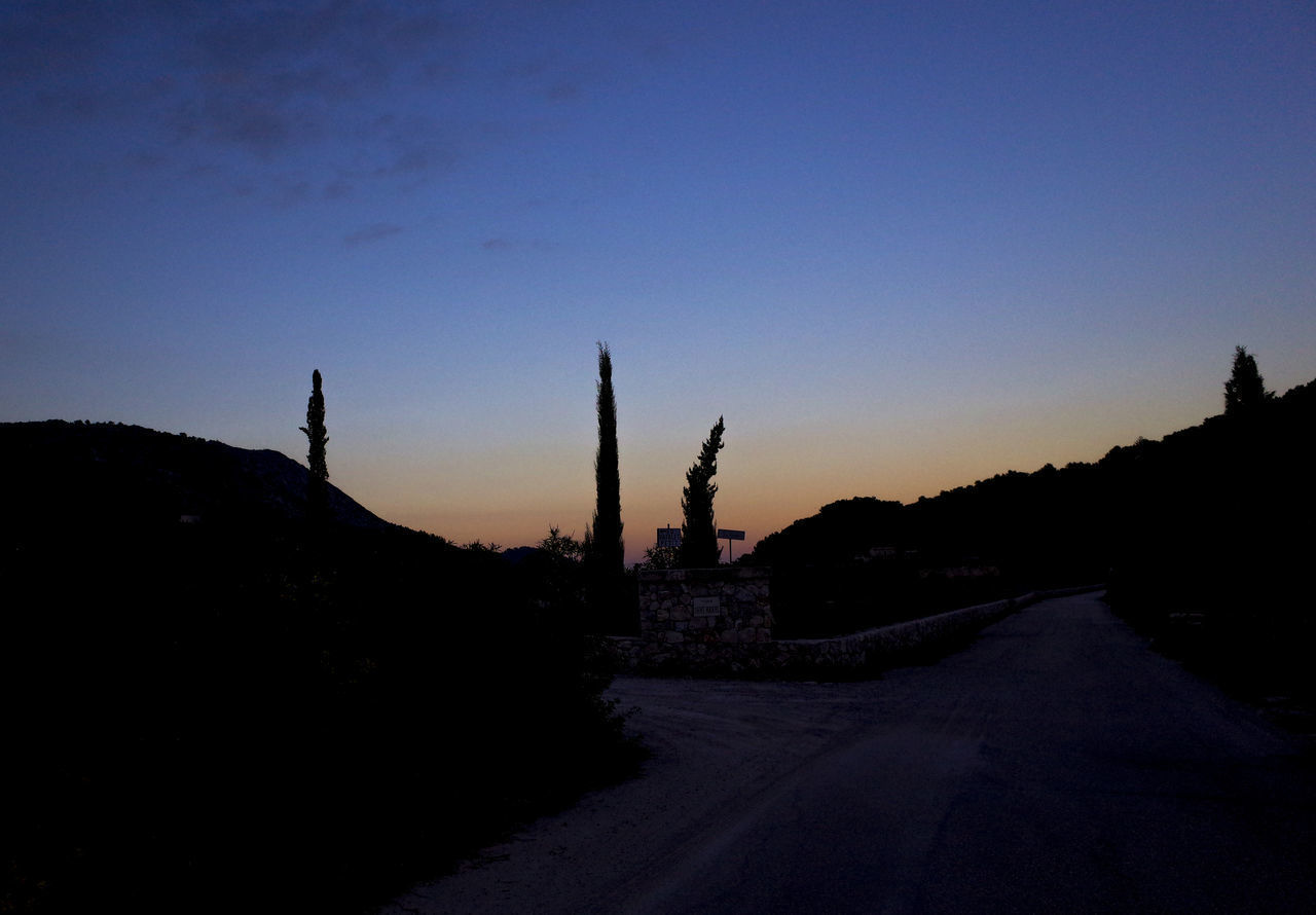 ROAD BY SILHOUETTE CITY AGAINST CLEAR SKY