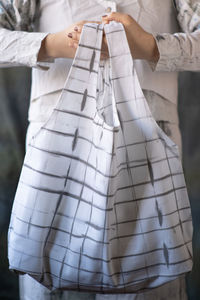 Midsection of woman holding paper while standing outdoors