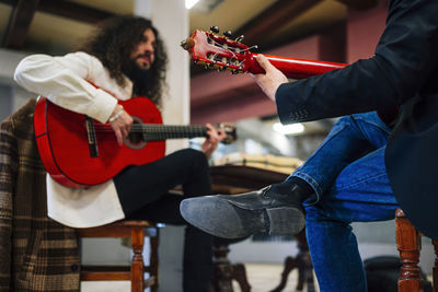 From below male friends playing guitars at table in music studio