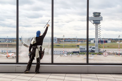 Rear view of man on glass window against sky